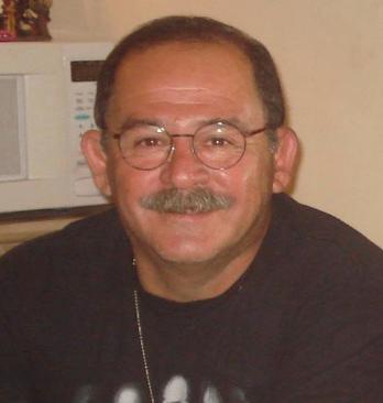 Hombre con bigote y gafas, mirando a la cámara sonriendo