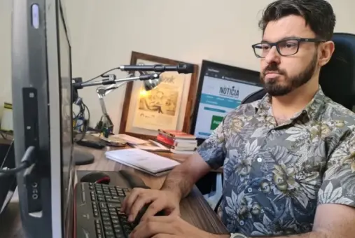  A man wearing glasses sits at a desktop, focused on the screen