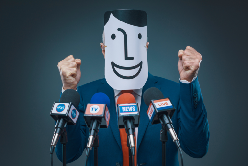 Politician with hands clenched at podium in front of news microphones